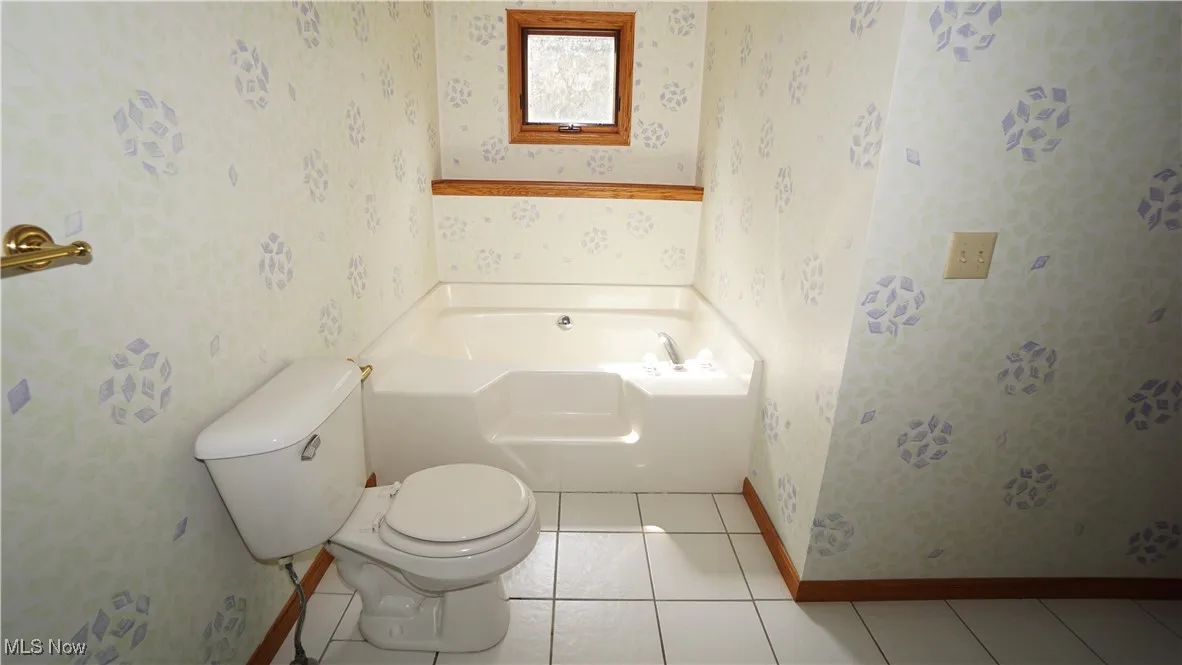 Primary bathroom featuring tile patterned flooring, wallpapered walls, and a garden tub