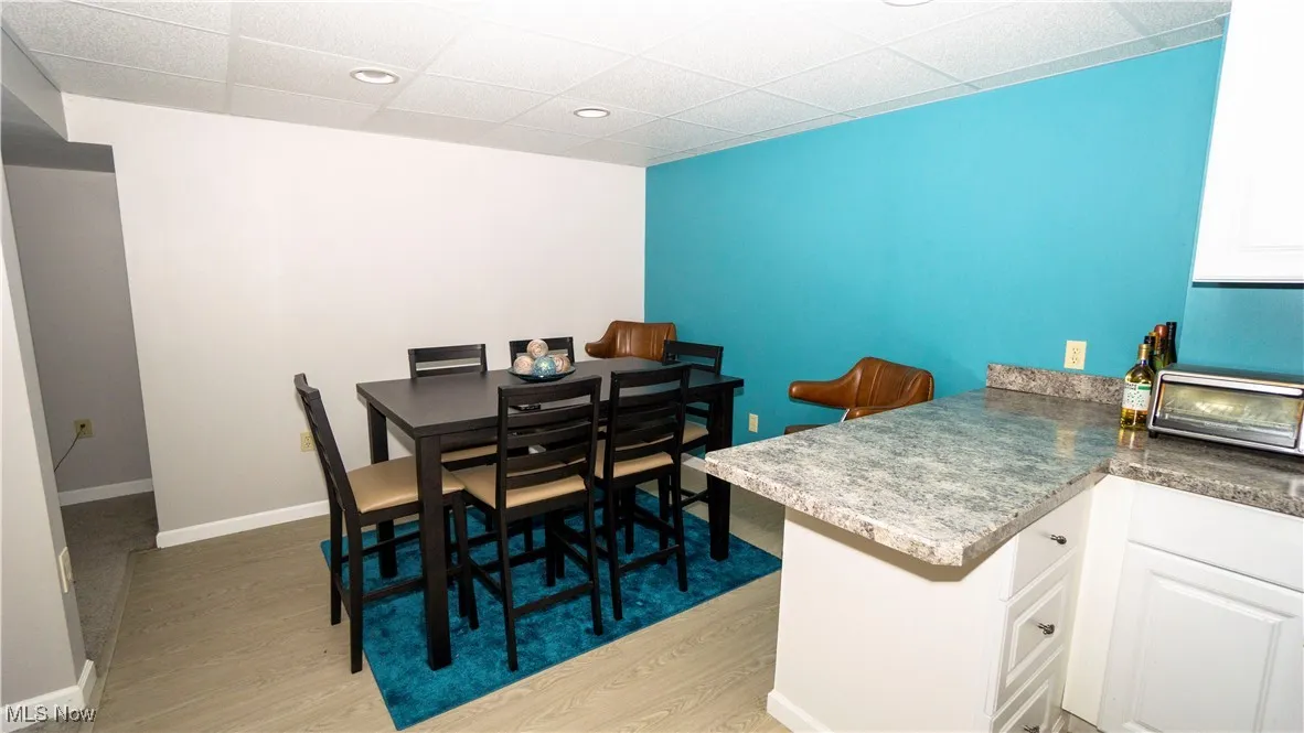 Kitchen and dining area in basement featuring a drop ceiling, light wood-style floors, and recessed lighting