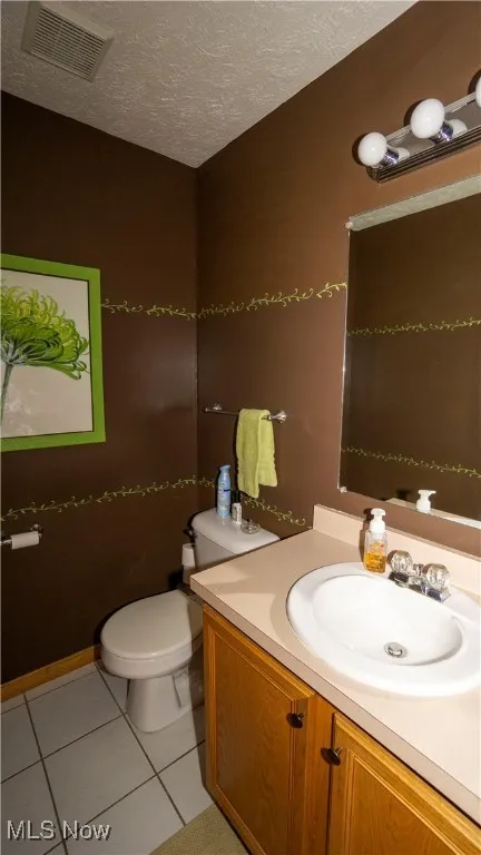 Half bath featuring vanity, a textured ceiling, and tile patterned flooring