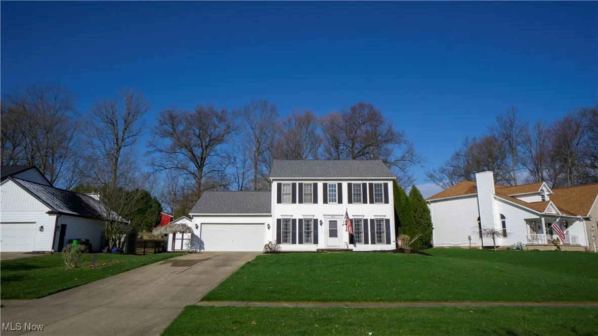 Colonial inspired home with a front lawn, driveway, and a garage