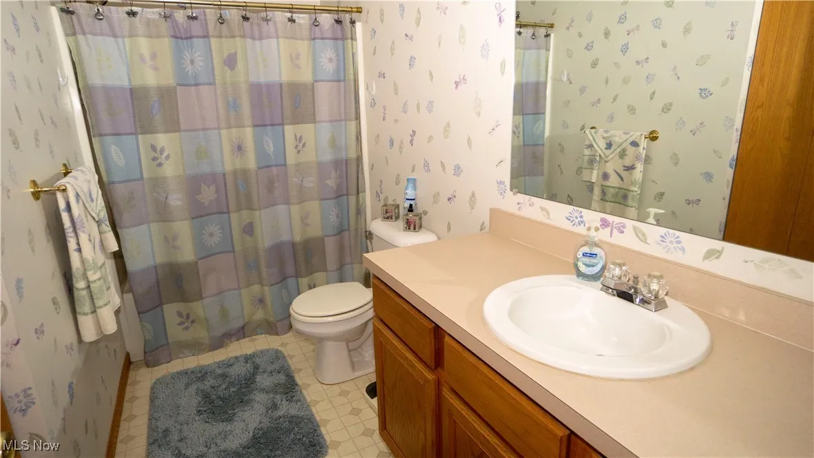 Bathroom with wallpapered walls, vanity, a shower with curtain, and tile patterned floors