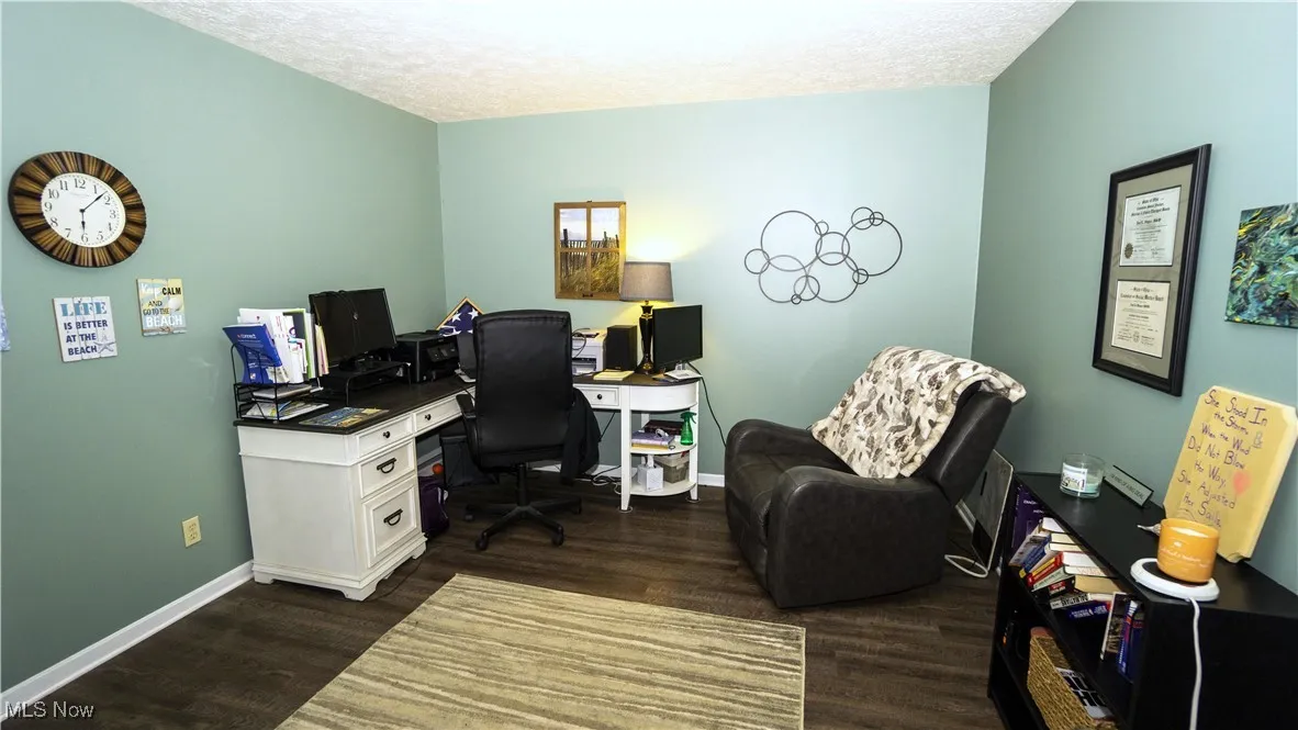 Office area featuring dark wood-style flooring and a textured ceiling