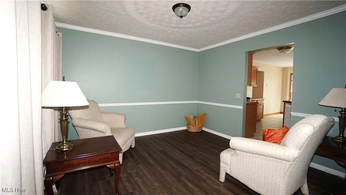 Living area featuring a textured ceiling, wood finished floors, and crown molding