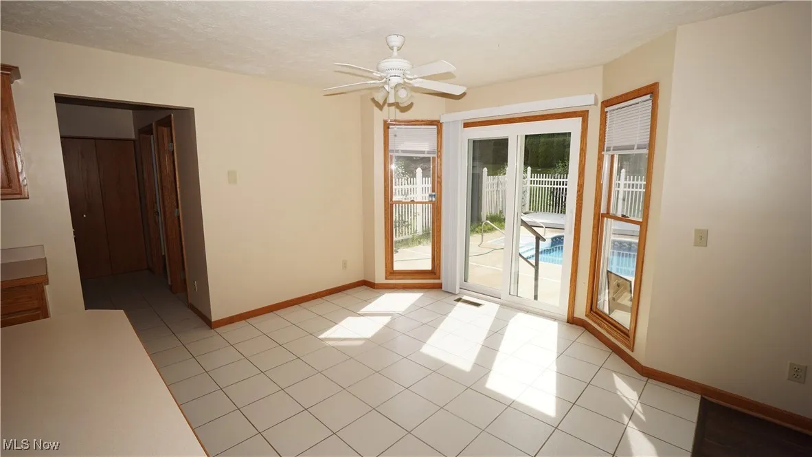 Doorway to outside featuring a textured ceiling, a ceiling fan, and light tile patterned floors