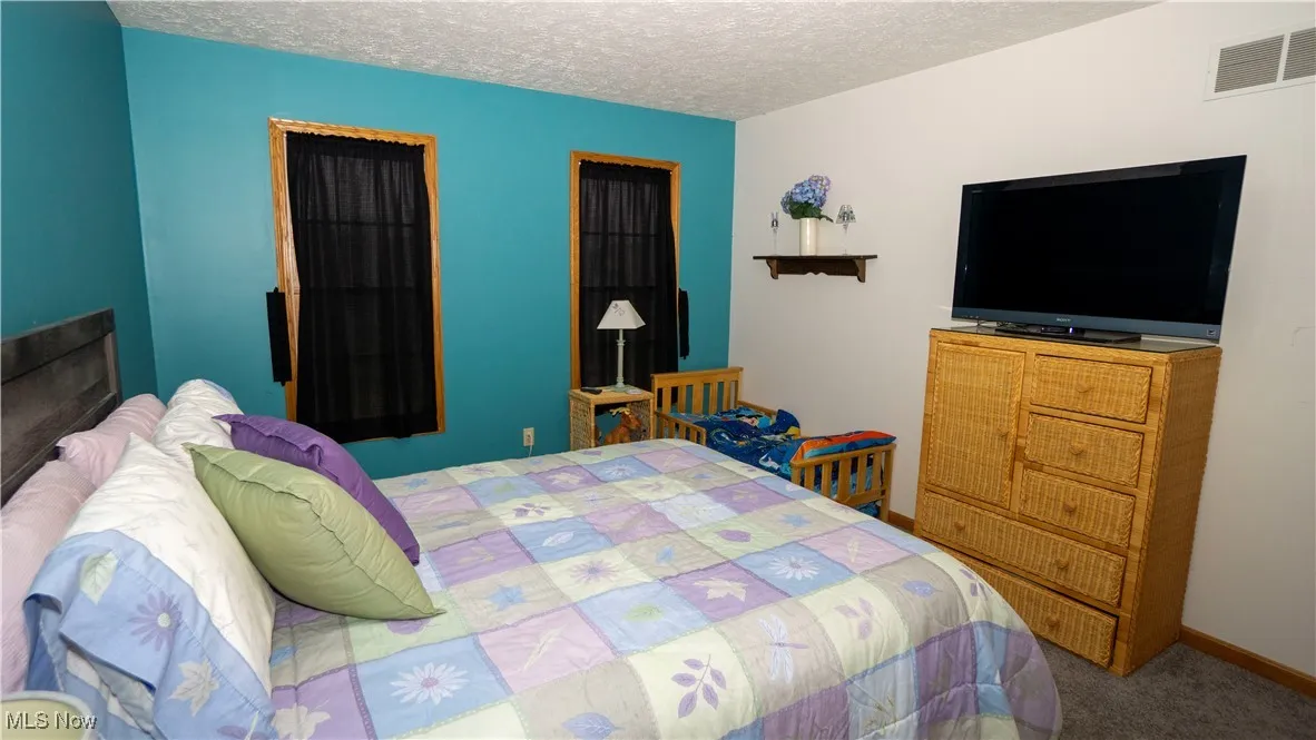 Bedroom with a textured ceiling and carpet flooring