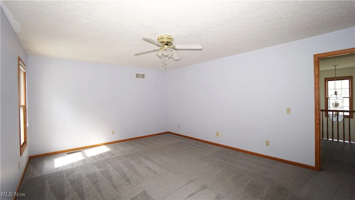 Unfurnished bedroom featuring carpet, a textured ceiling, and a ceiling fan