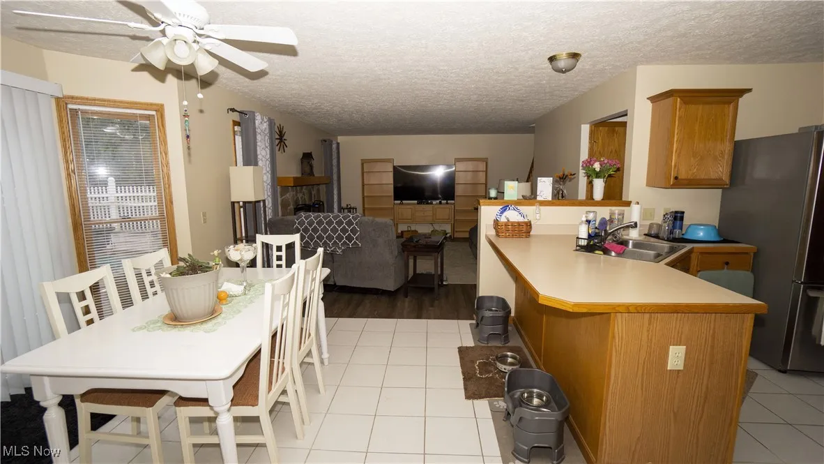Kitchen and breakfast area with a textured ceiling, light tile patterned floors, and a ceiling fan