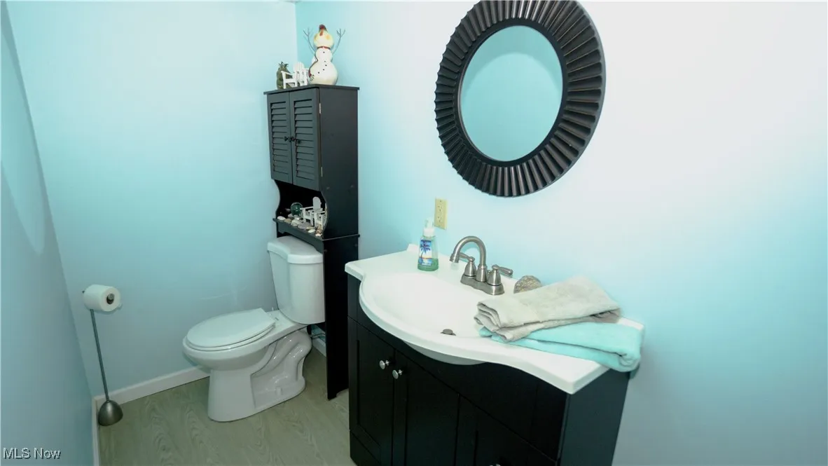 Half bath in basement featuring vanity and wood finished floors