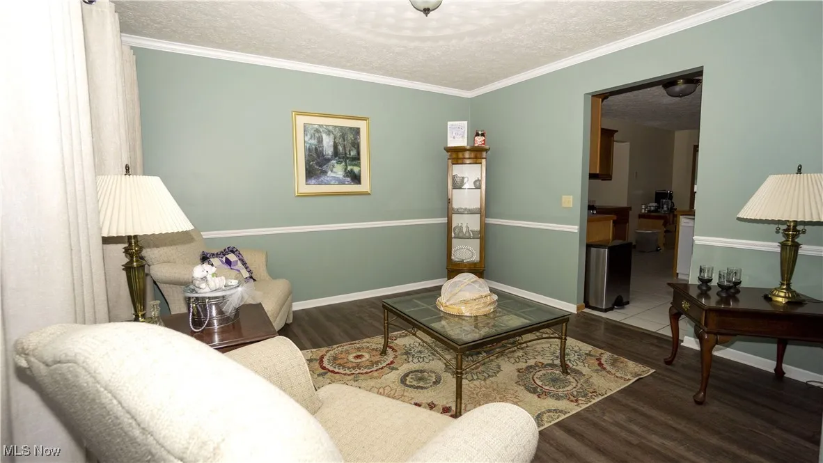 Living room featuring a textured ceiling, wood finished floors, and ornamental molding