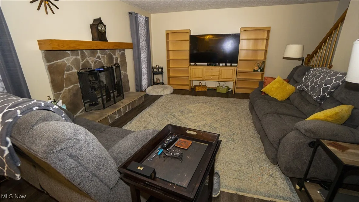 Family room with wood finished floors, a stone fireplace, and a textured ceiling