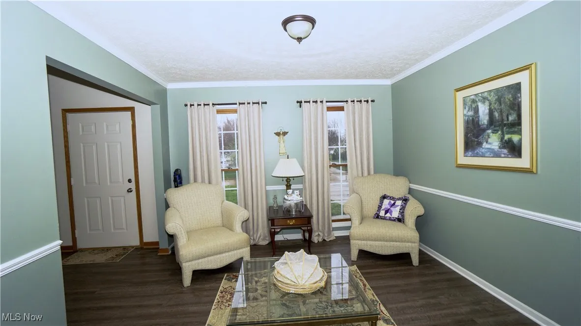Living area featuring wood finished floors, ornamental molding, and a textured ceiling