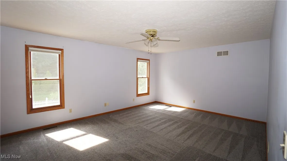 Primary Bedroom featuring carpet floors, a textured ceiling, and a ceiling fan