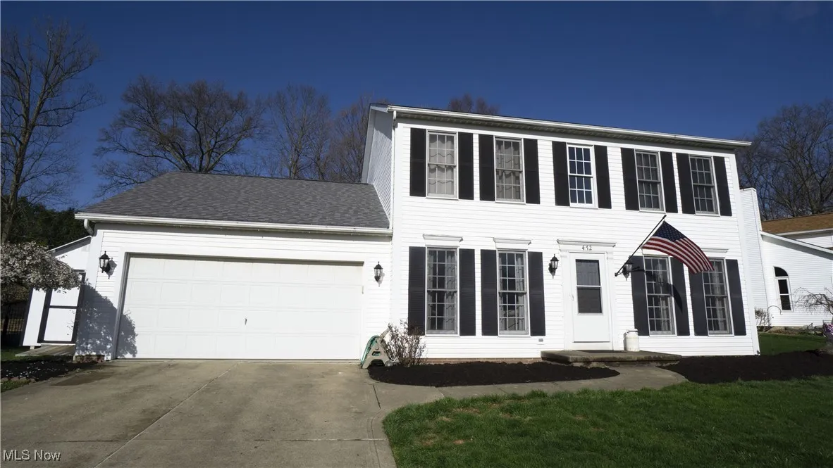Colonial-style house with an attached garage, driveway, and a shingled roof