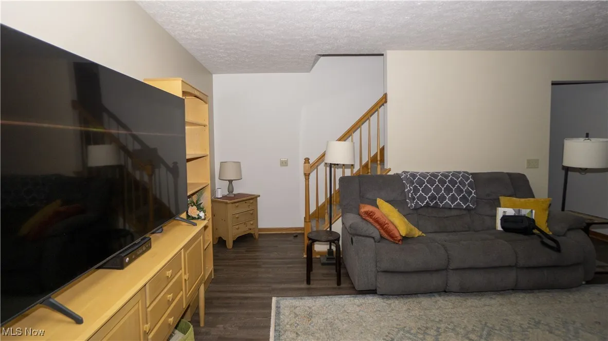 Family room featuring dark wood-type flooring, stairs, and a textured ceiling