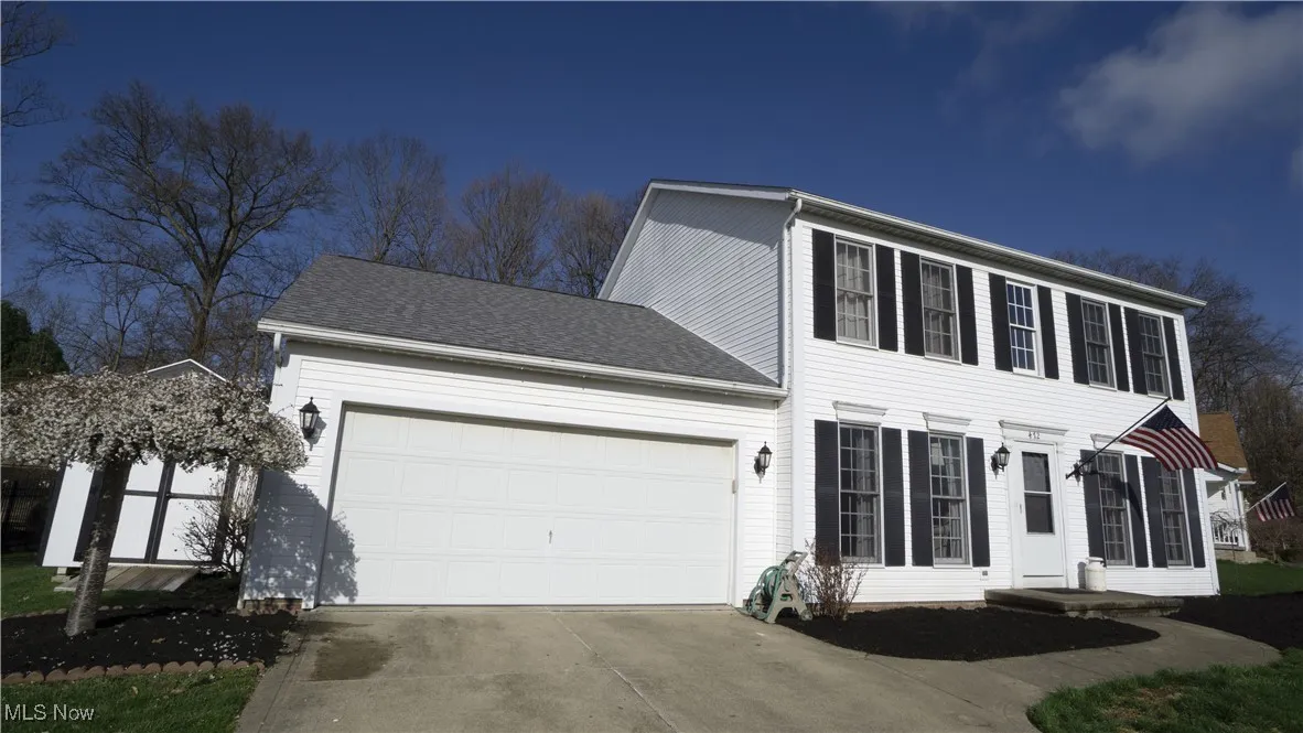 Colonial home featuring an attached garage, concrete driveway, and a shingled roof
