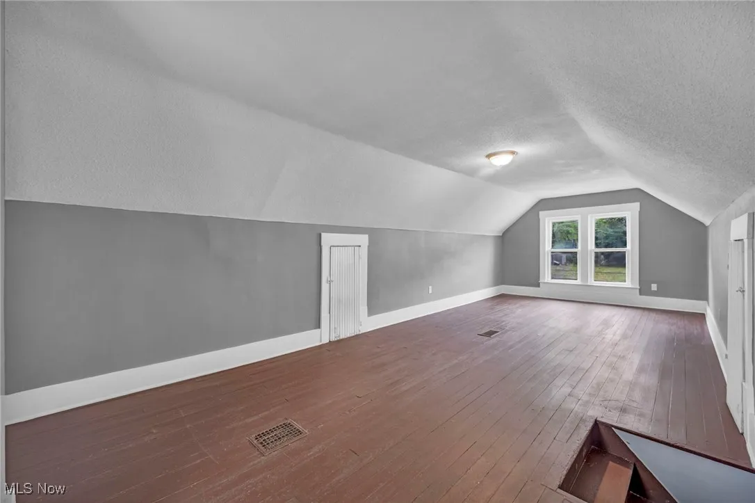 Bonus room with vaulted ceiling, a textured ceiling, and wood-type flooring