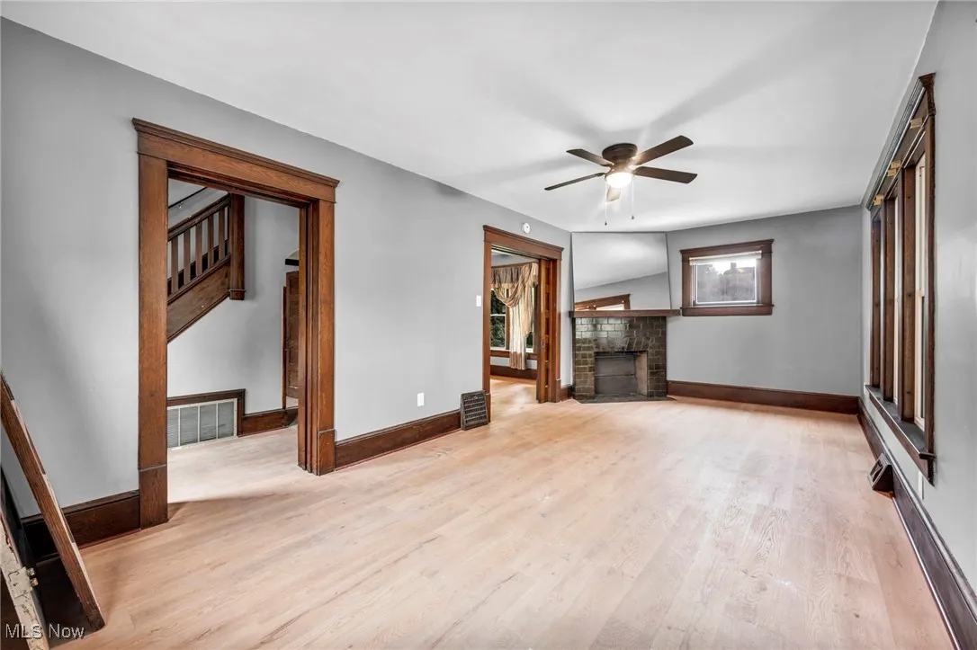 Unfurnished living room with light wood-type flooring, a brick fireplace, and ceiling fan