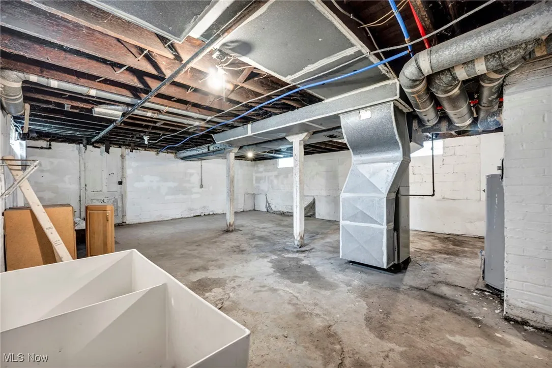 Unfinished basement featuring heating unit and gas water heater