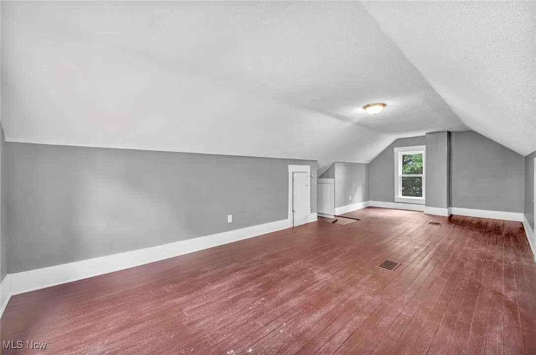 Additional living space with lofted ceiling, wood finished floors, and a textured ceiling