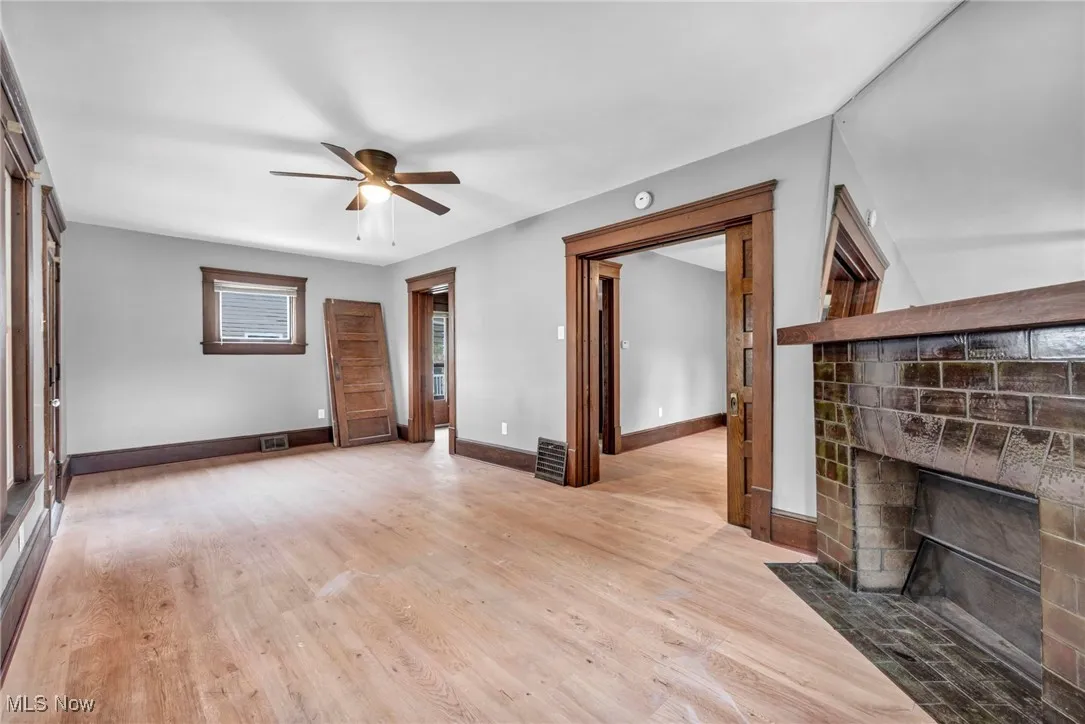 Unfurnished living room featuring light wood-type flooring, a fireplace with flush hearth, and a ceiling fan