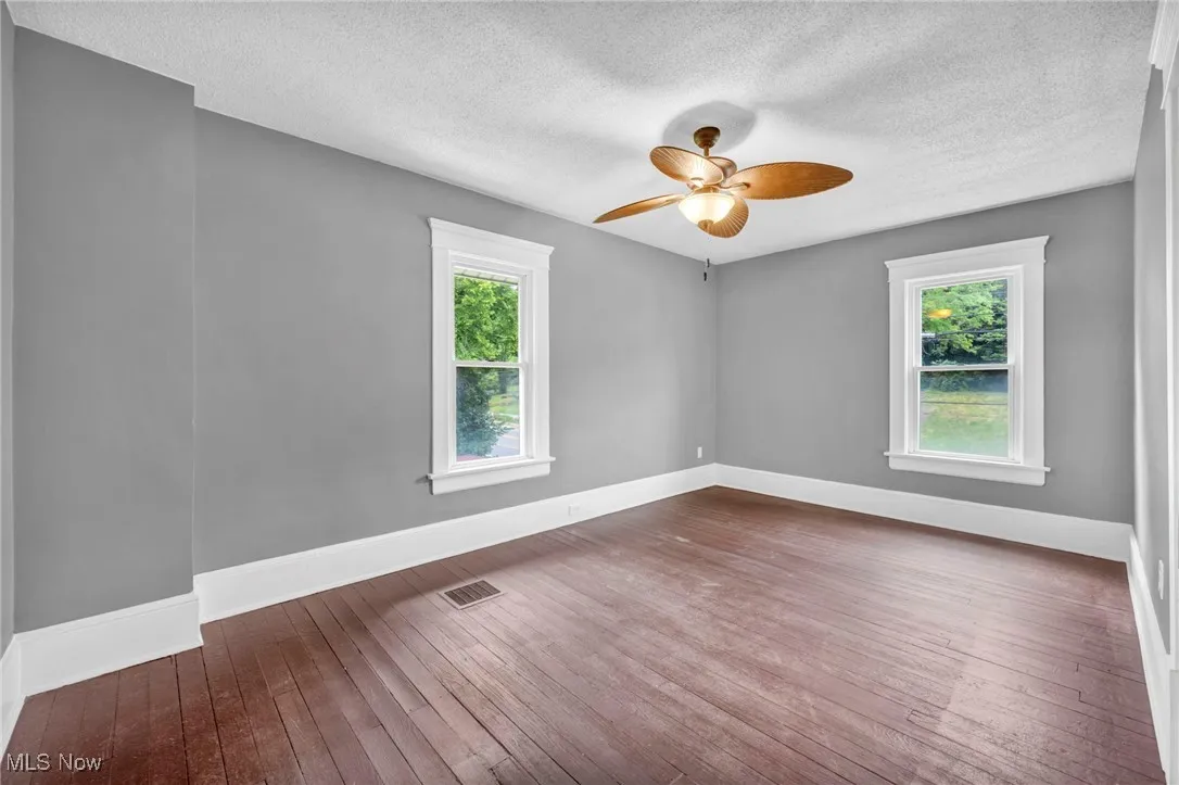Empty room with wood-type flooring, a textured ceiling, and a ceiling fan