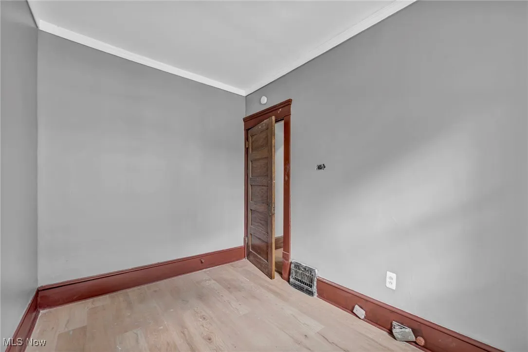 Empty room featuring wood finished floors and ornamental molding