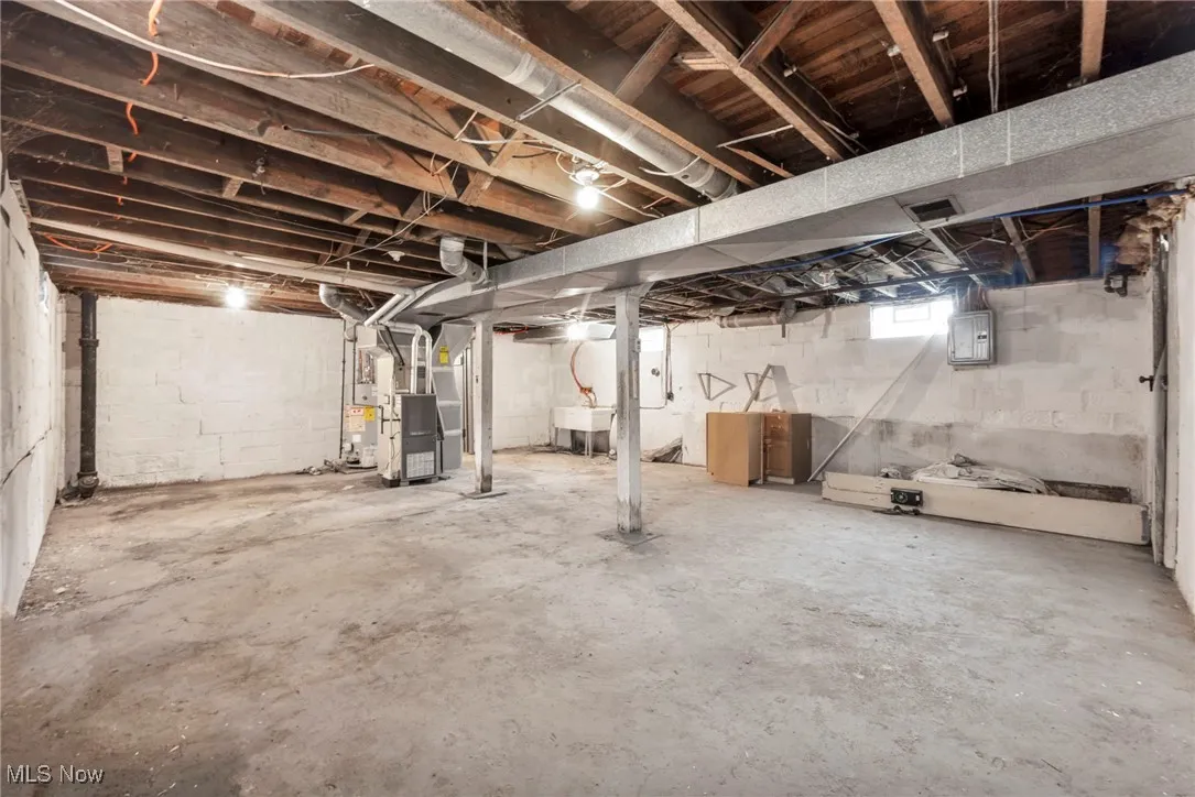 Below grade area featuring heating unit, electric panel, and water heater