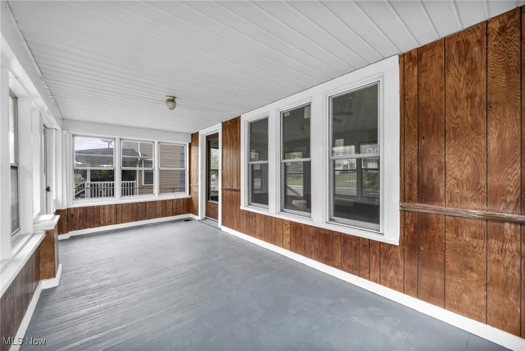 Unfurnished sunroom with wood walls and baseboards