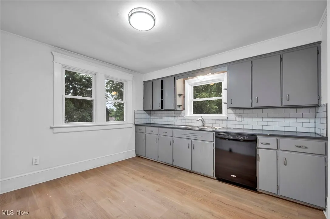 Kitchen with dark countertops, gray cabinetry, black dishwasher, and tasteful backsplash