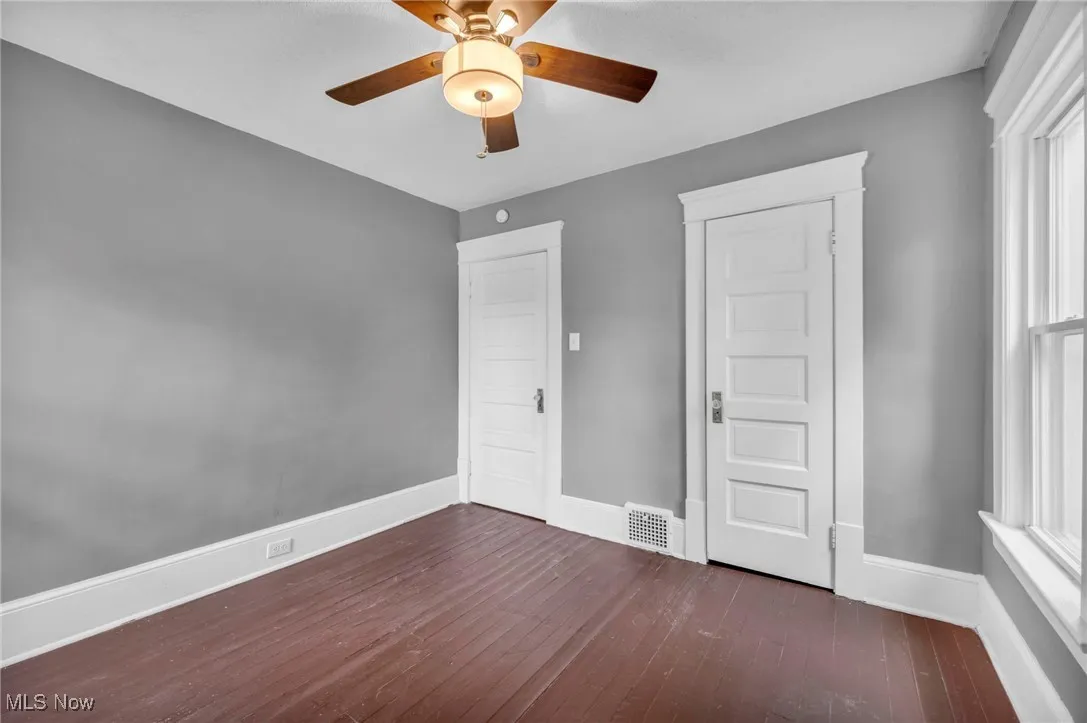 Unfurnished bedroom featuring dark wood-style flooring and a ceiling fan