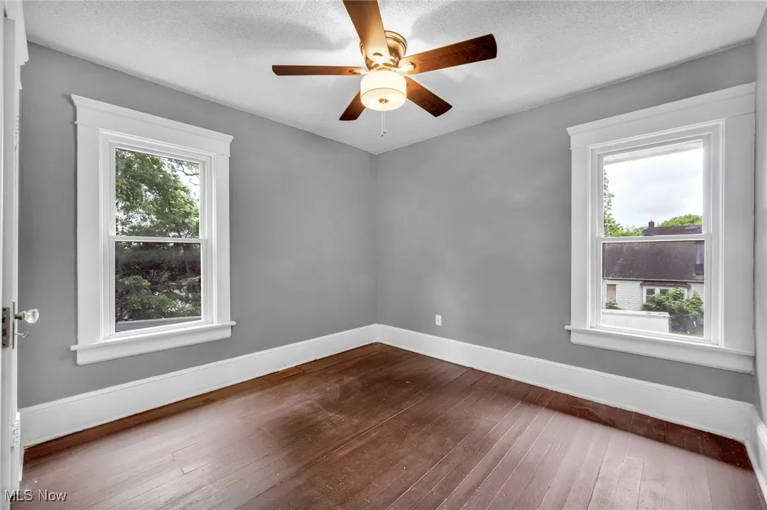 Spare room featuring dark wood-type flooring, a textured ceiling, and a ceiling fan