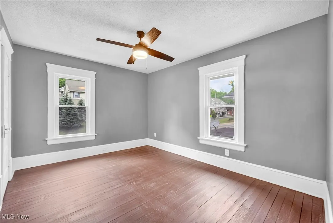 Unfurnished room featuring hardwood / wood-style floors, a textured ceiling, plenty of natural light, and a ceiling fan