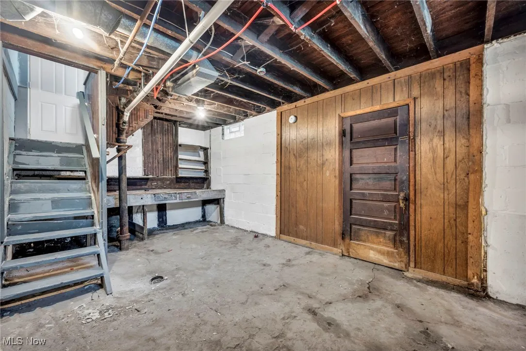 Unfinished basement with wood walls and stairway