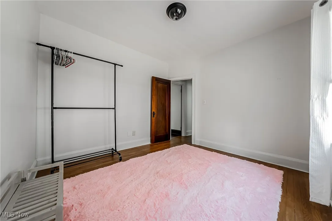Unfurnished bedroom with baseboards and dark wood-style flooring