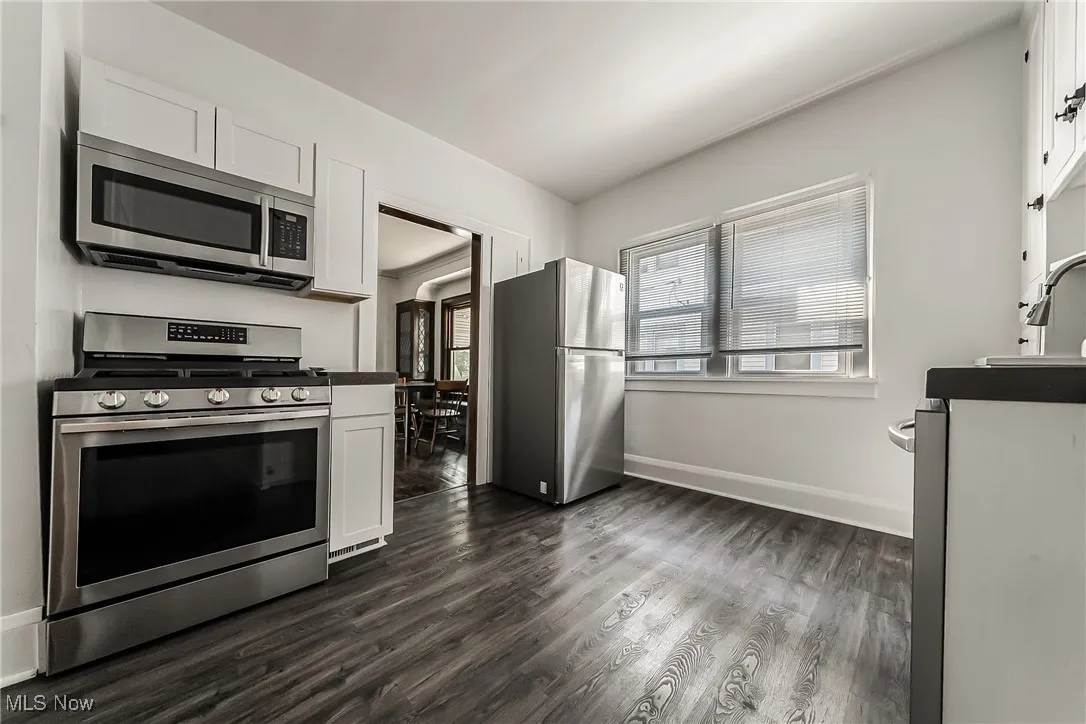 Kitchen with appliances with stainless steel finishes, dark wood finished floors, and white cabinets