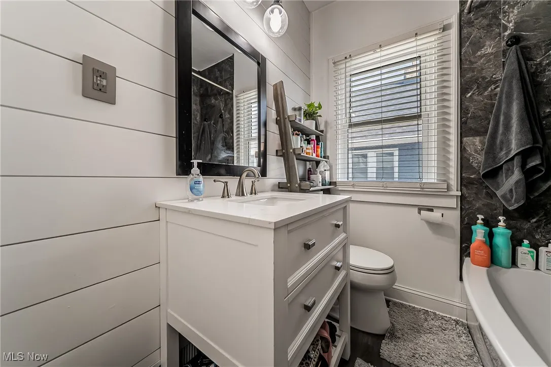 Full bath featuring vanity and wooden walls