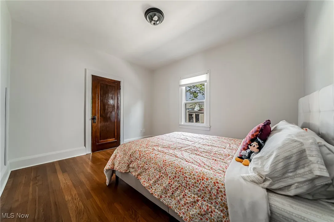 Bedroom with dark wood-style floors and baseboards