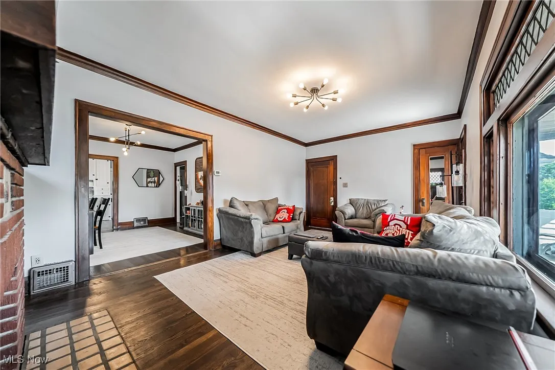 Living area with a chandelier, crown molding, and dark wood finished floors