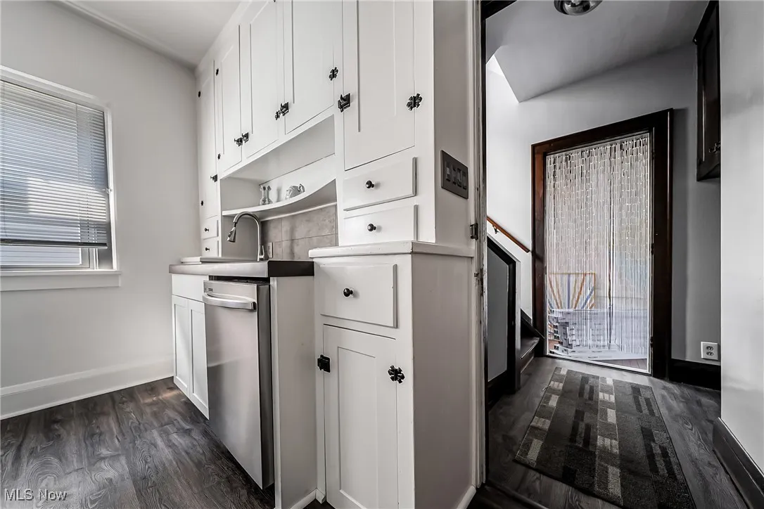 Kitchen featuring open shelves, white cabinets, dark wood-style flooring, and dishwasher