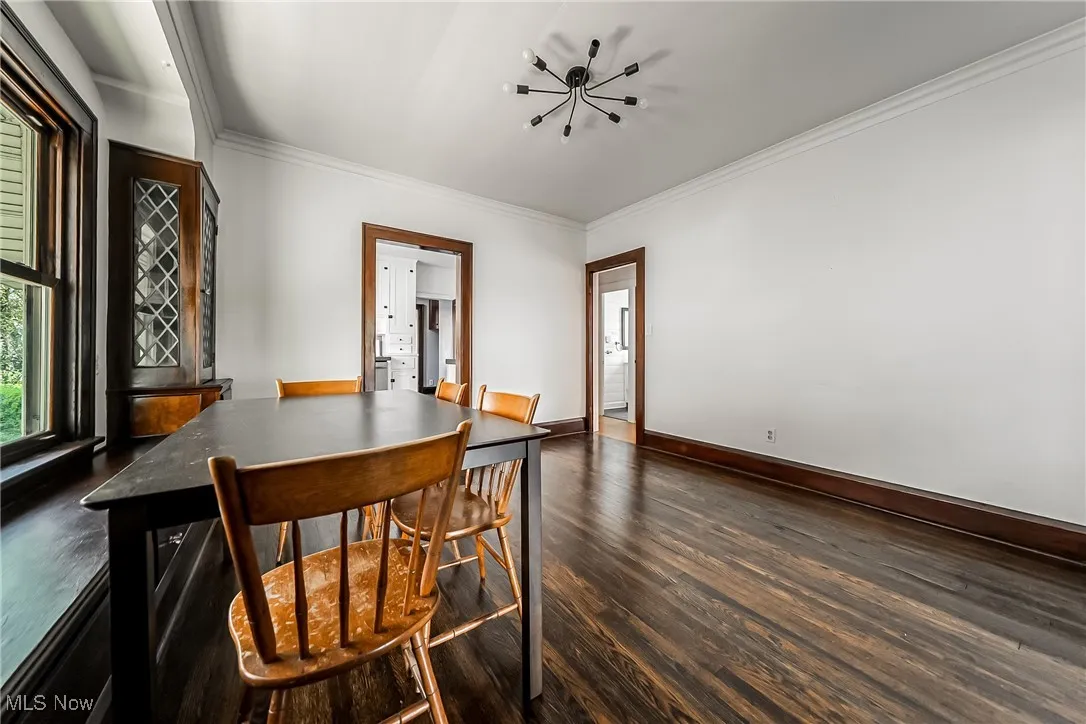 Dining area featuring dark wood-style floors, crown molding, and a chandelier