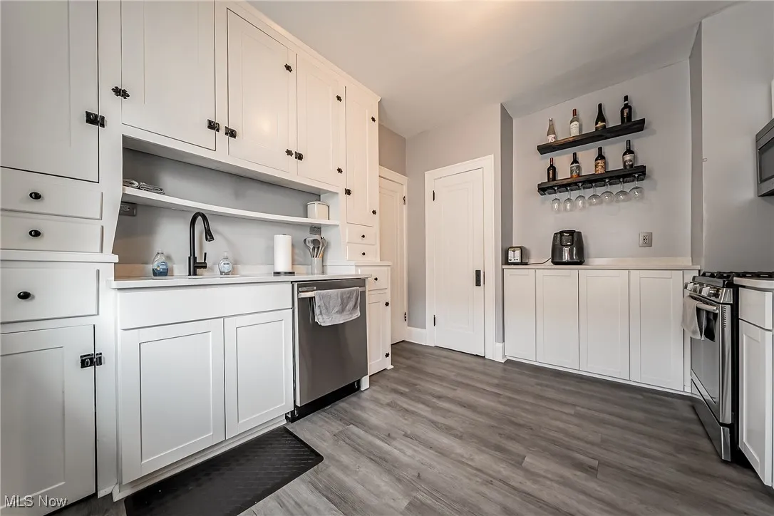 Kitchen featuring open shelves, stainless steel appliances, wood finished floors, and light countertops