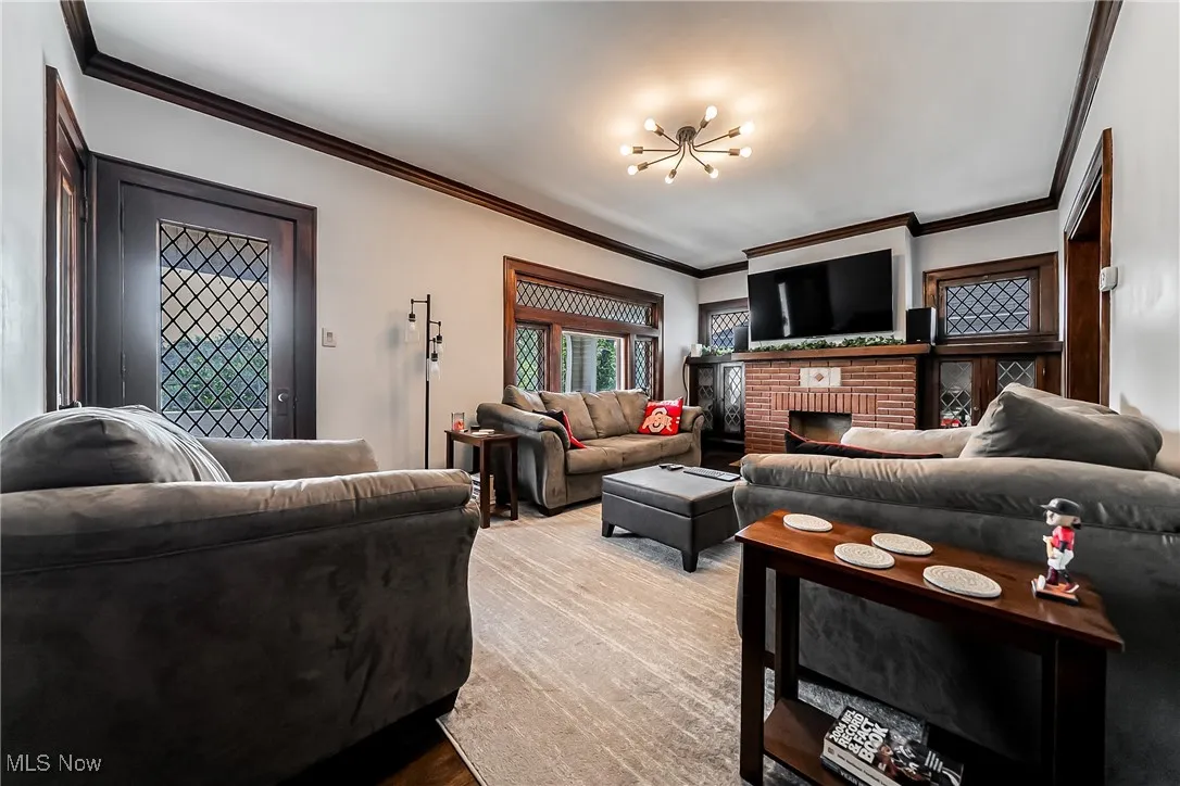 Living area featuring crown molding, a chandelier, and a fireplace