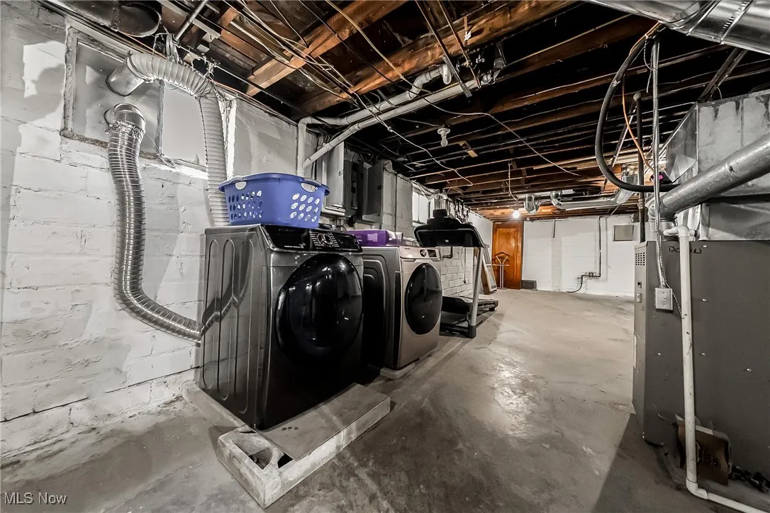 Unfinished below grade area featuring washer and clothes dryer and heating unit