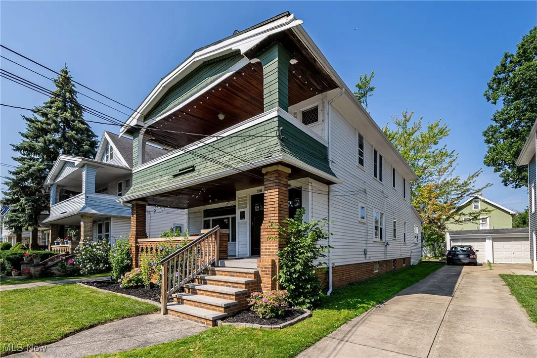 View of front facade with covered porch, an outdoor structure, a front yard, and a garage