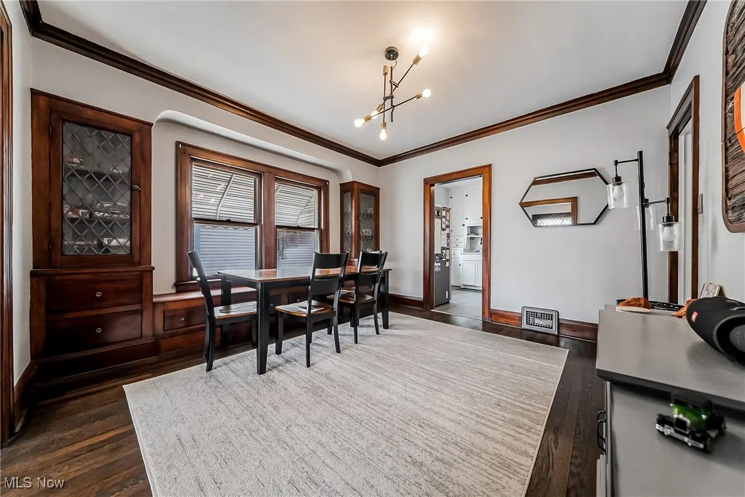 Dining space featuring ornamental molding, dark wood-type flooring, and a chandelier
