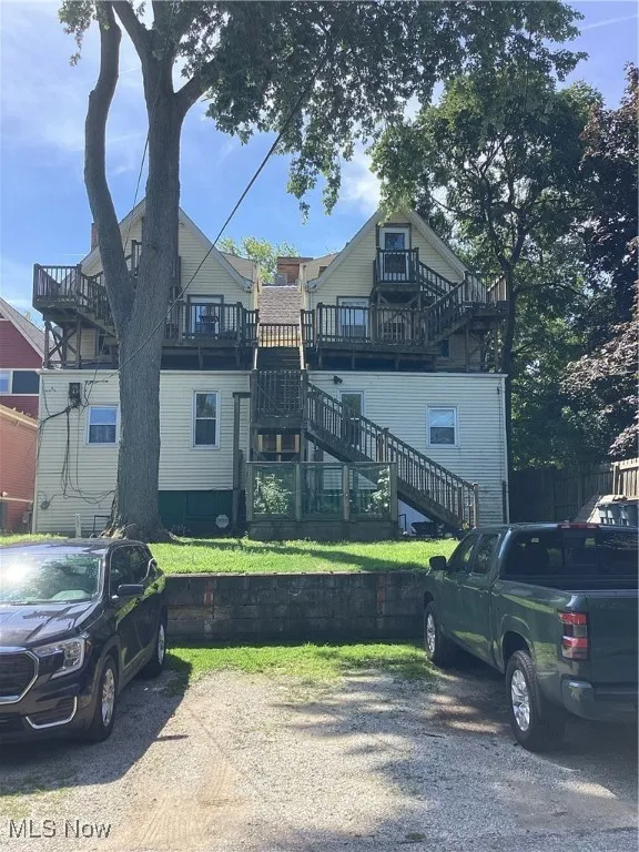 View of front of property featuring stairs, a deck, and a front lawn
