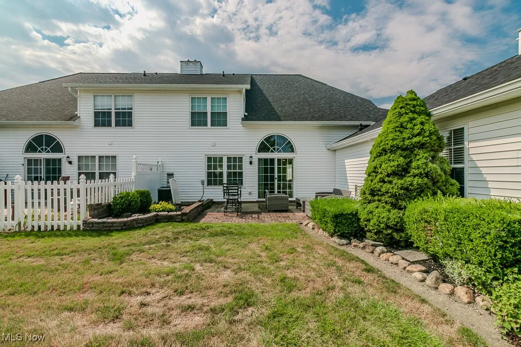 Rear view of property featuring a chimney, a shingled roof, and a patio area