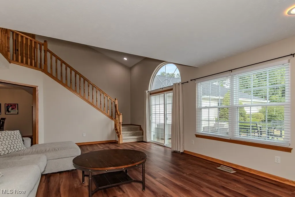Living room featuring stairway, dark wood-type flooring, and recessed lighting