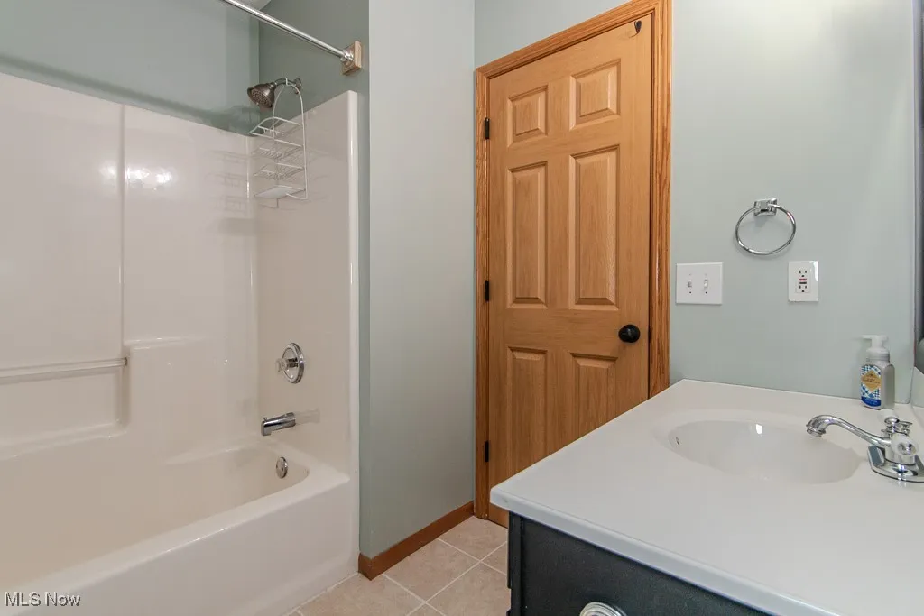 Bathroom with tile patterned floors, shower / washtub combination, and vanity