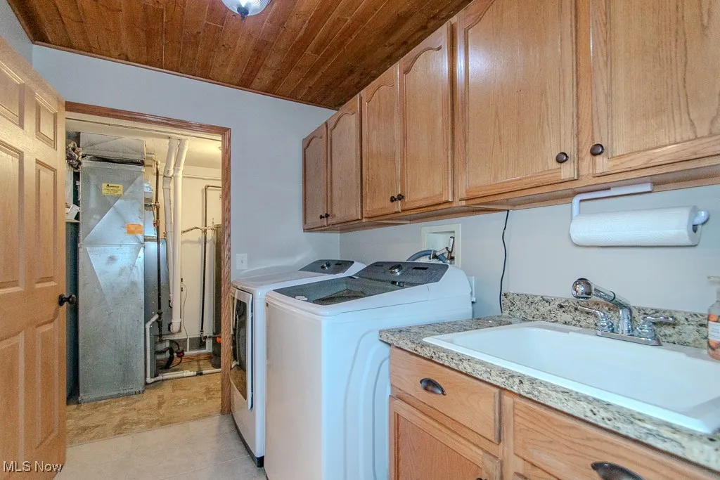 Laundry room featuring washer and dryer, heating unit, wood ceiling, and light tile patterned flooring